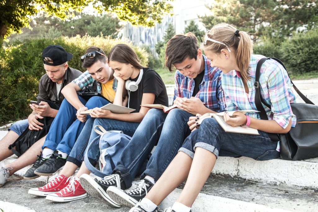 group-of-young-students-with-books-and-gadgets-sit-on-the-steps-in-the-park-Image