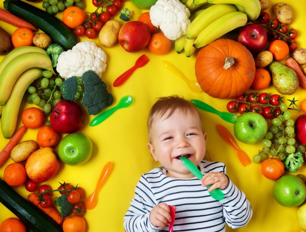 happy-baby-surrounded-by-fresh-fruit-and-veggies